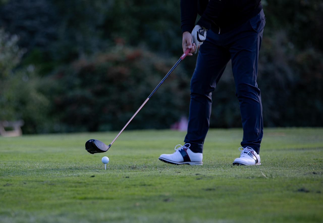 Person with a golf club about to swing at a golf ball