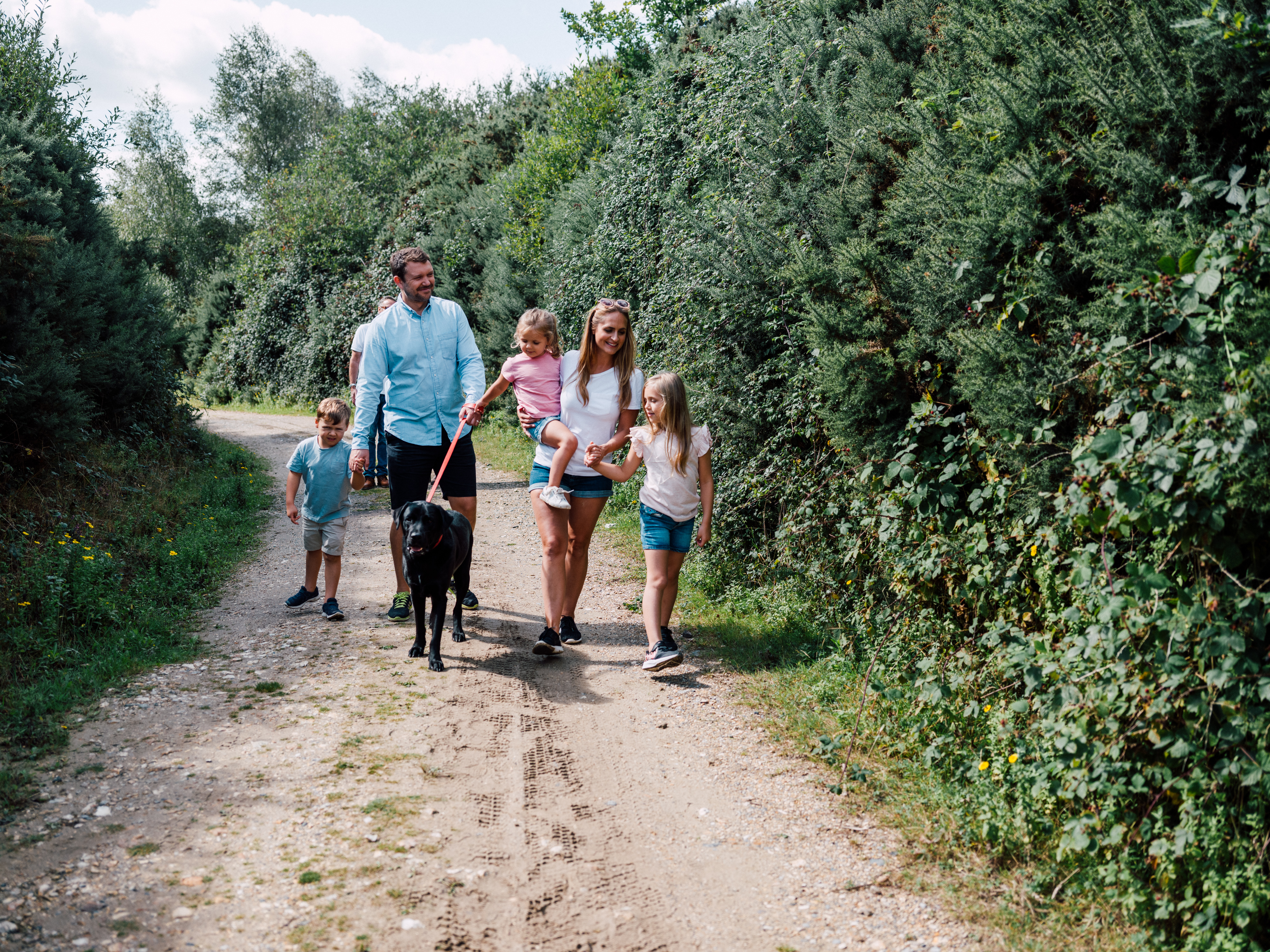 A family with a black dog on a hike