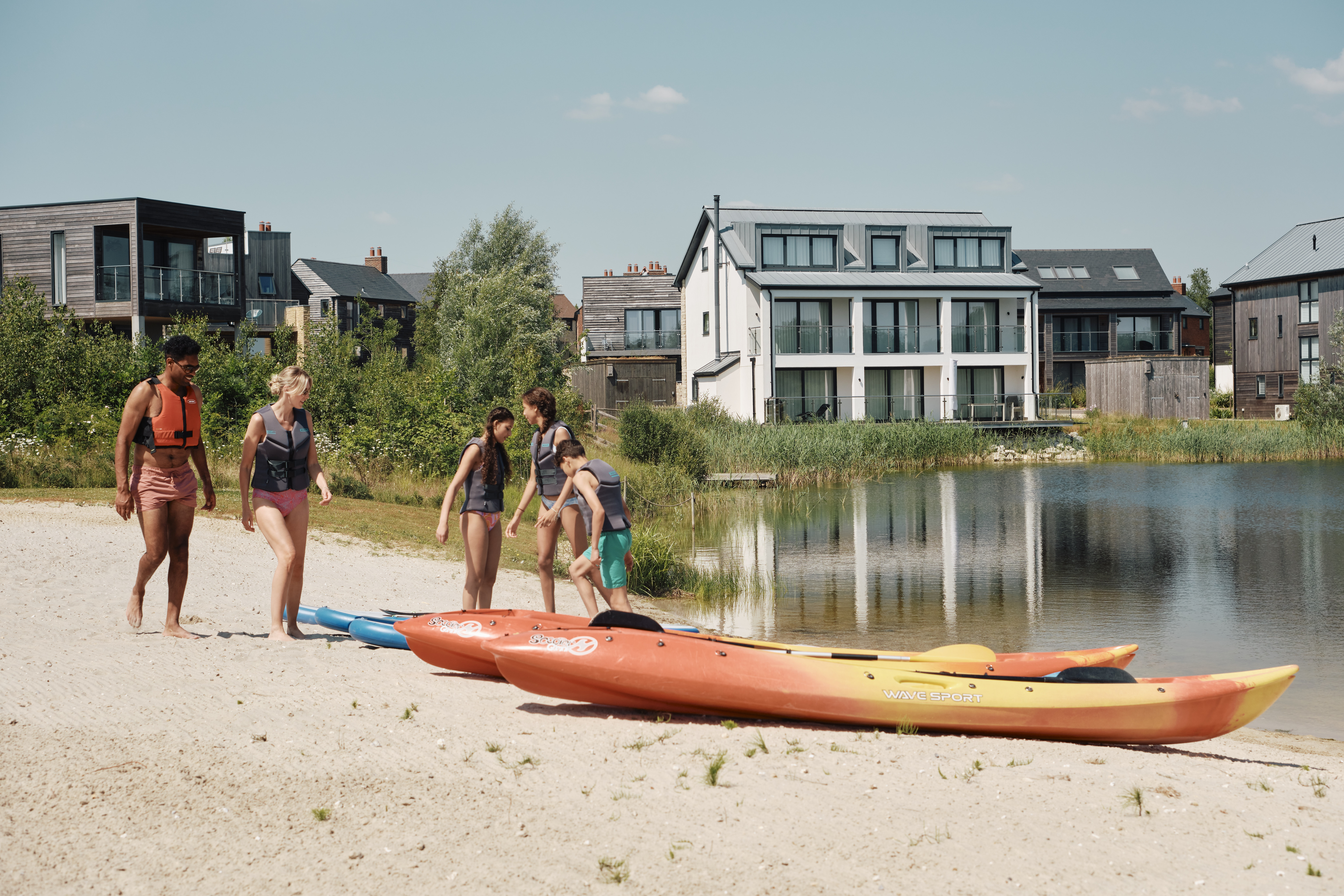 A family getting into canoes on the shore of a lake